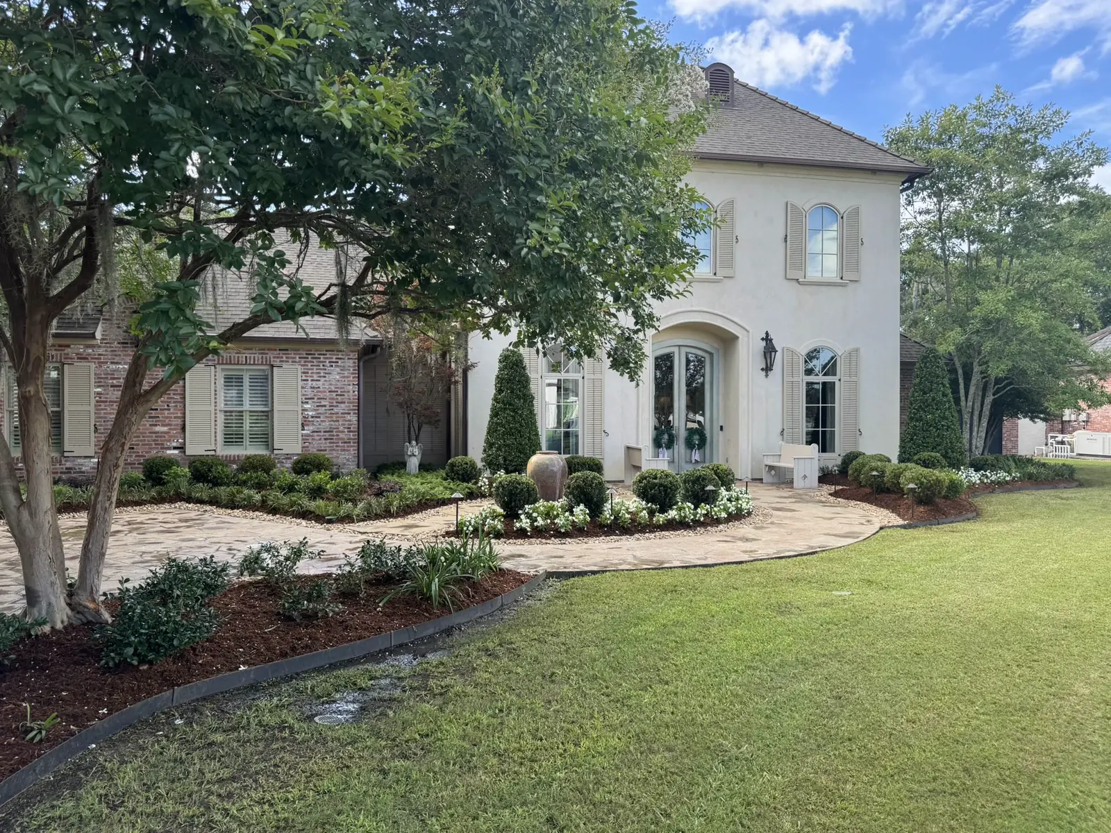 Front yard with a curved paver walkway, turf, and foundation plantings