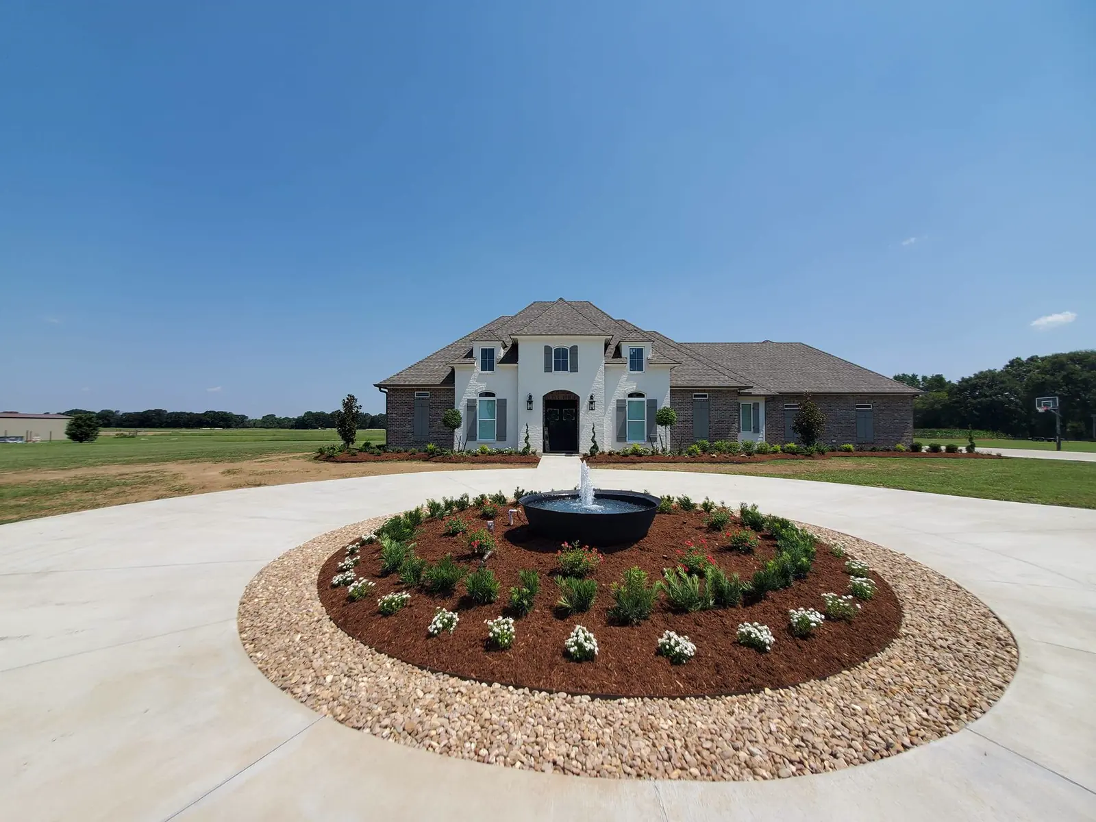 Brick house front yard with turf, foundation beds, and a small ornamental tree